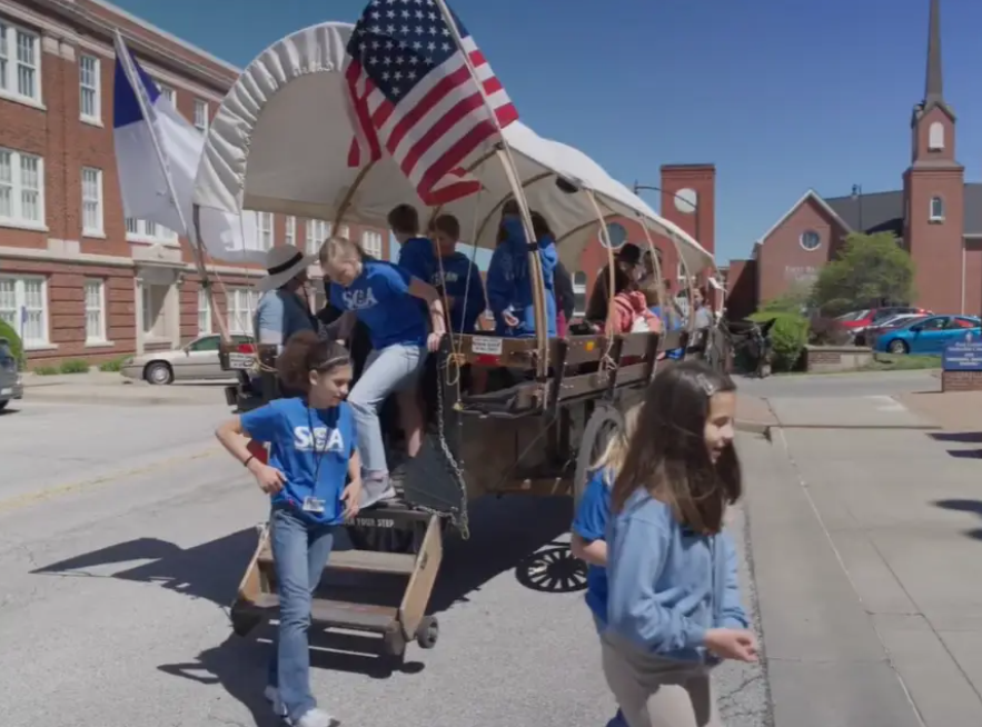 Students pulling a covered wagon in an Independence parade